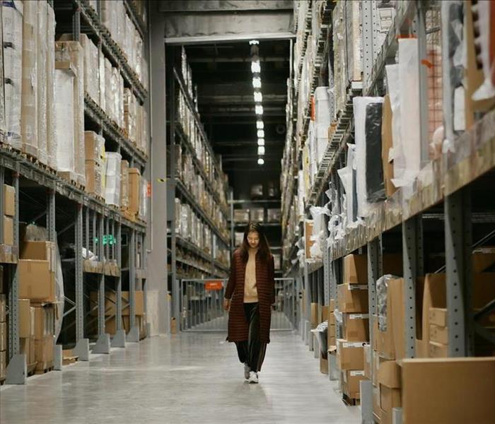 A woman walks down an aisle in a warehouse